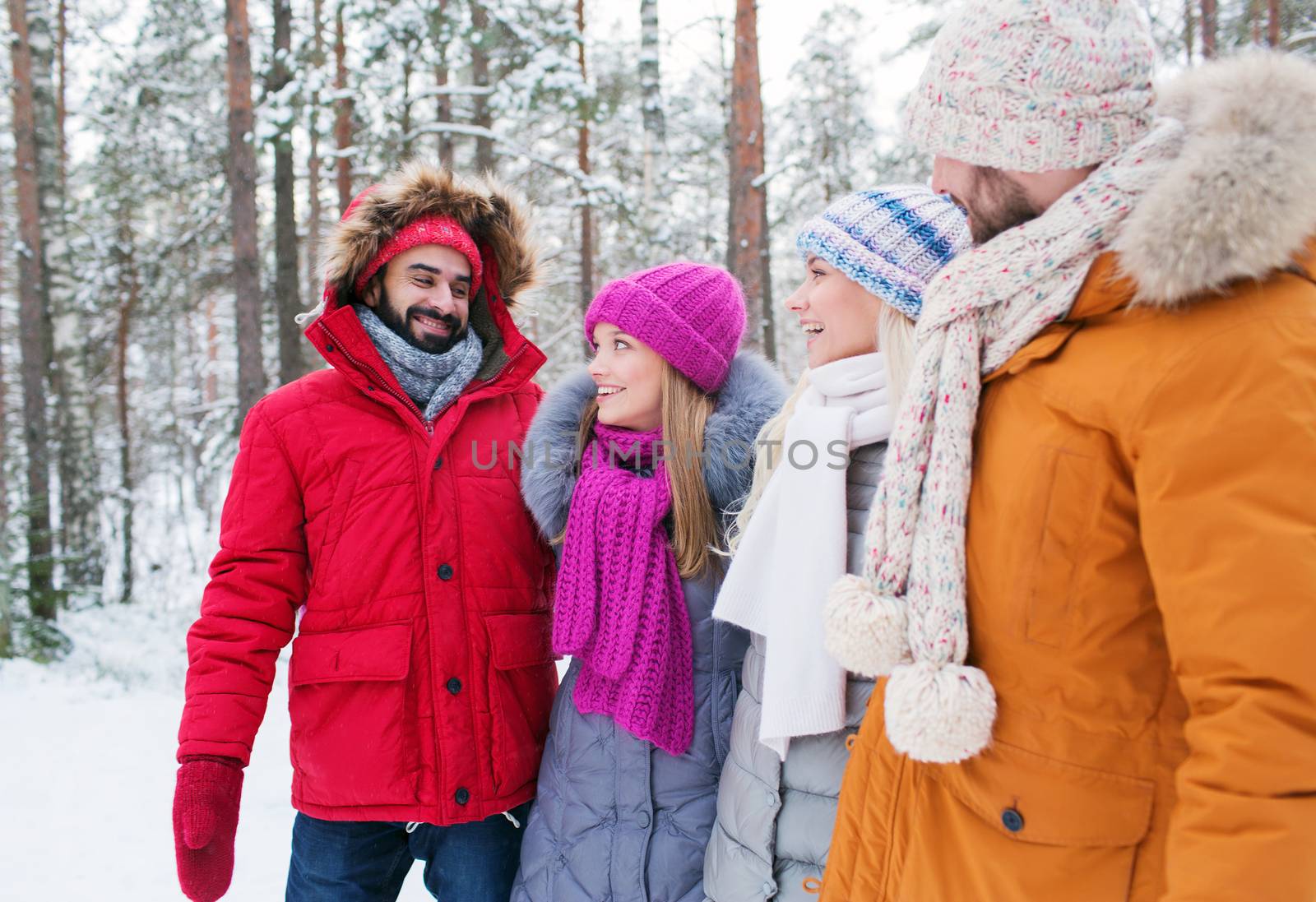 group of smiling men and women in winter forest by dolgachov