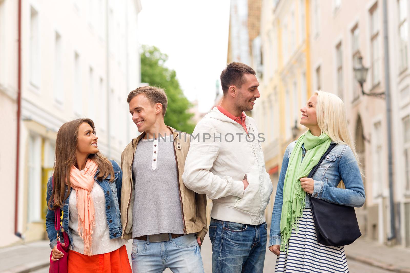 group of smiling friends walking in the city by dolgachov