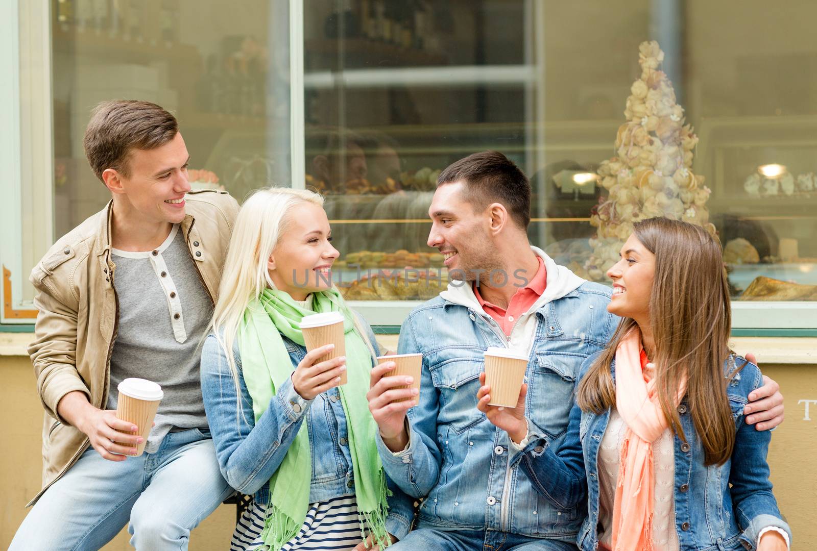 friendship, travel, drink and vacation concept - group of smiling friends with take away coffee