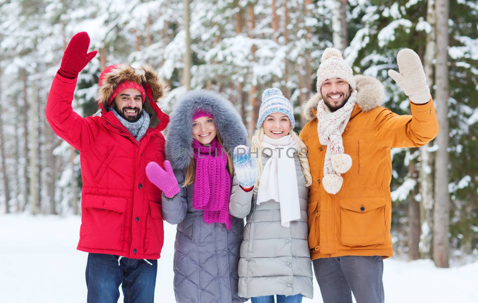 love, relationship, season, friendship and people concept - group of smiling men and women waving hands in winter forest