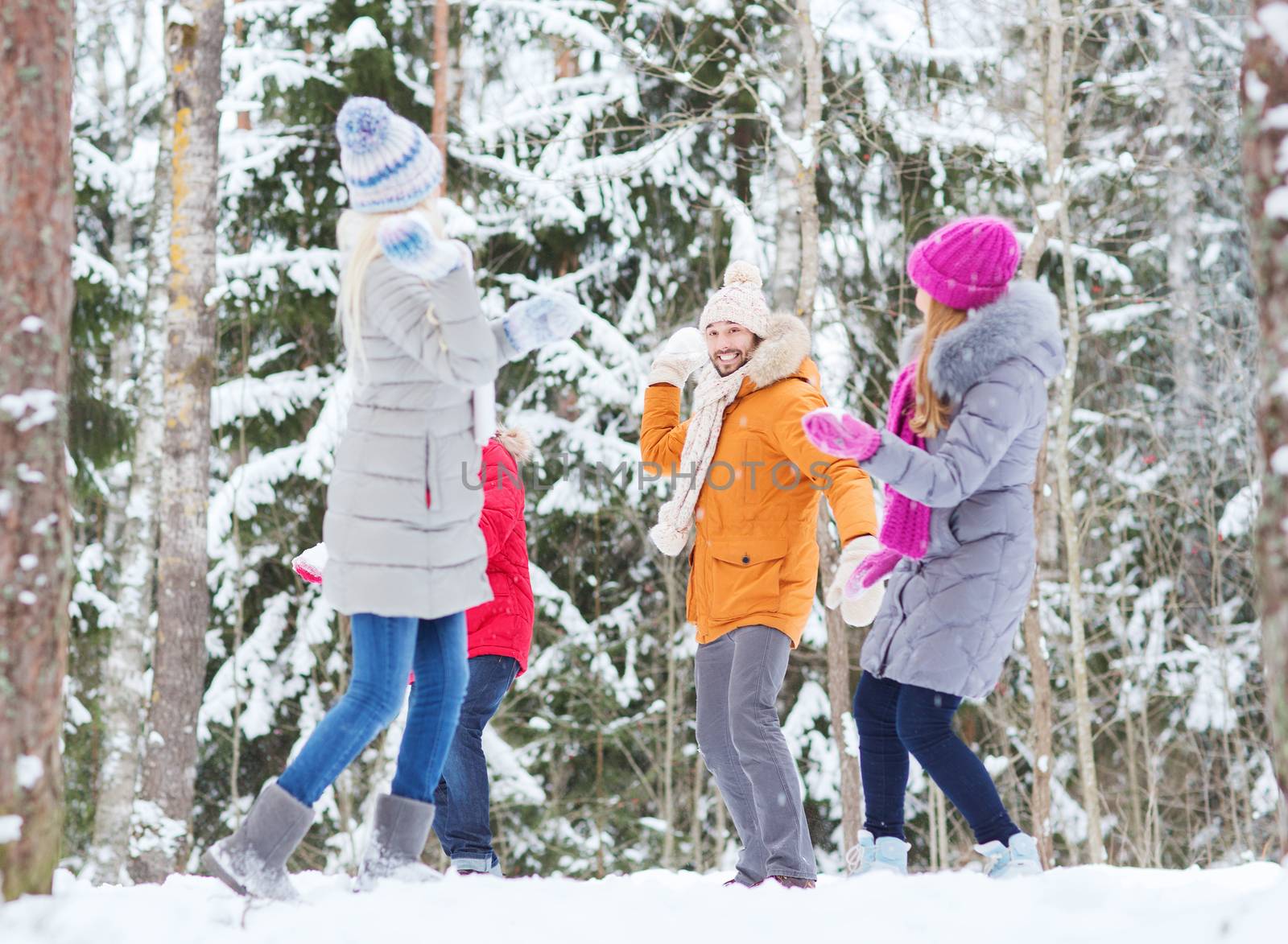 group of happy friends playing snowballs in forest by dolgachov