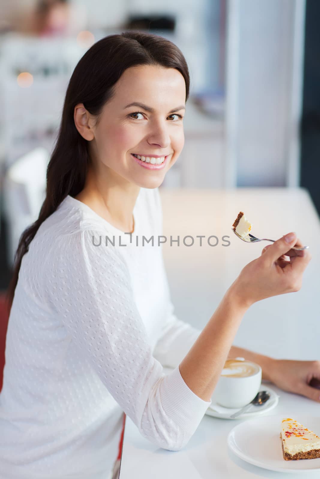 smiling young woman with cake and coffee at cafe by dolgachov