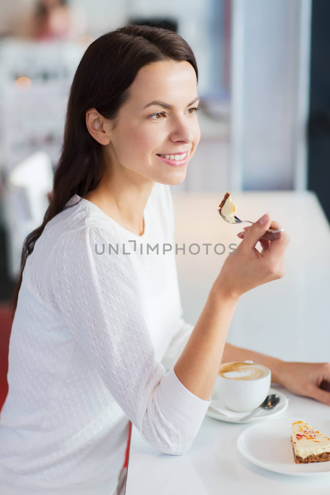 smiling young woman with cake and coffee at cafe by dolgachov