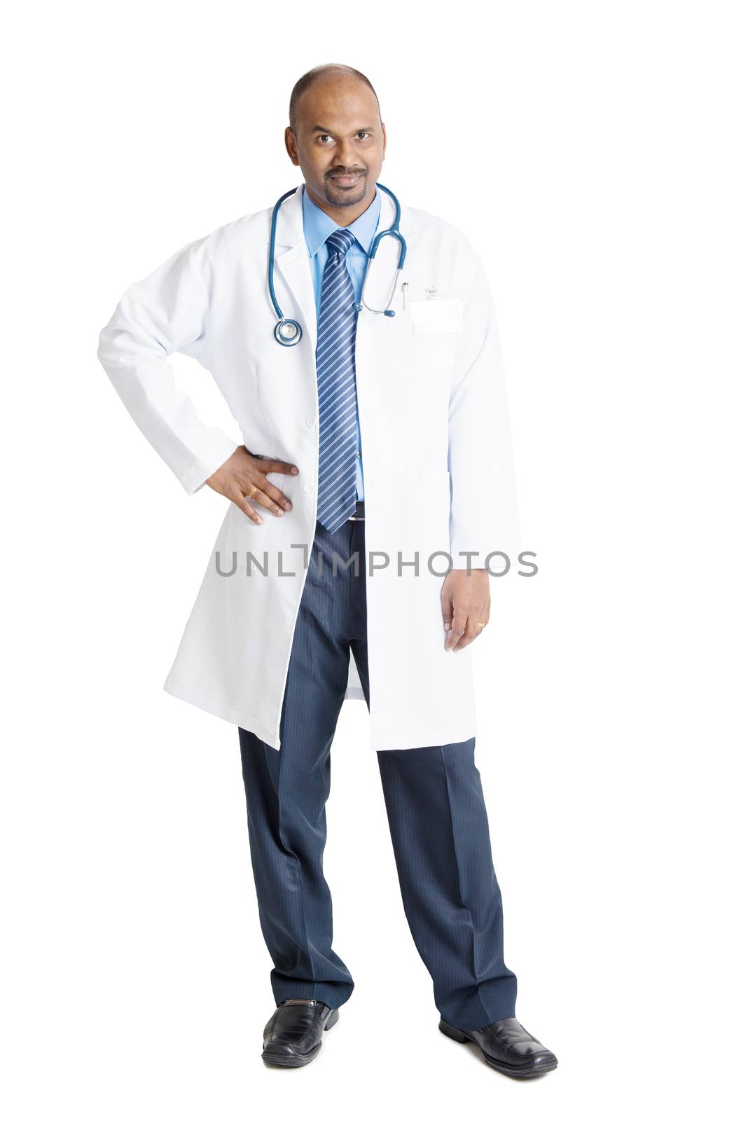 Full length mature Indian male medical doctor in uniform standing isolated on white background.