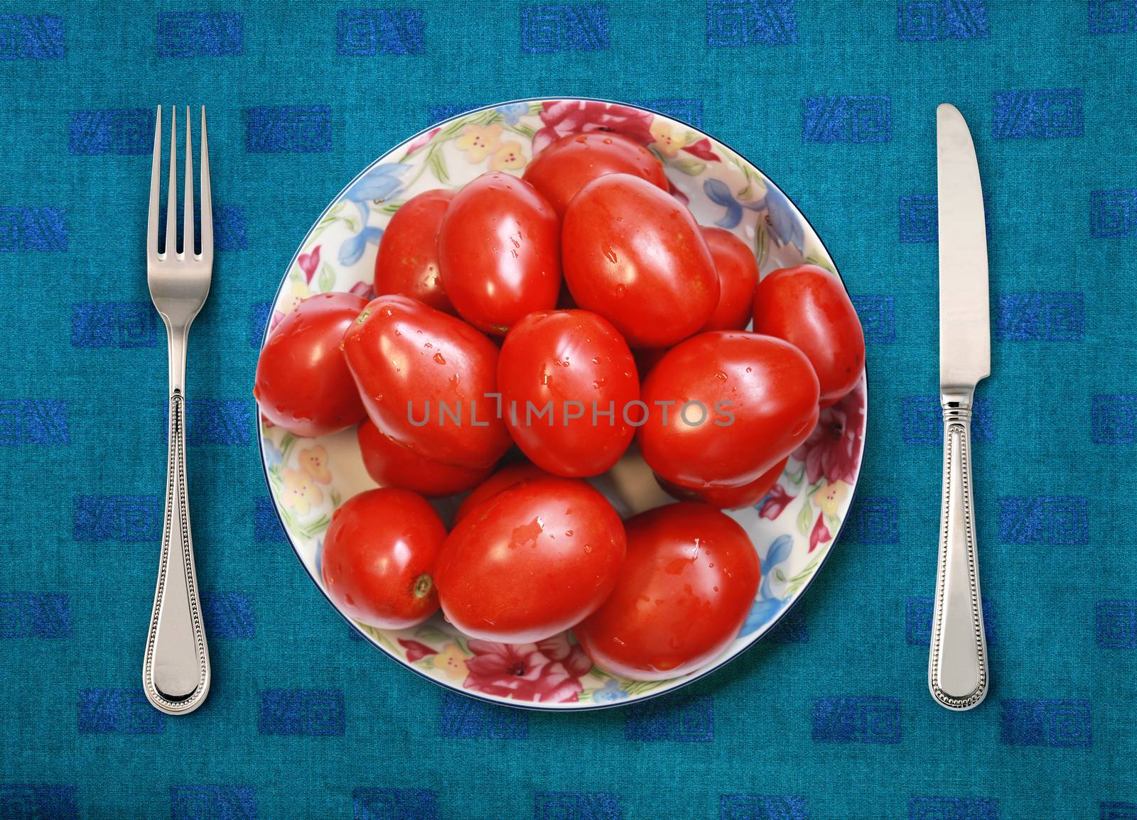 red tomatoes on white plate, knife and fork