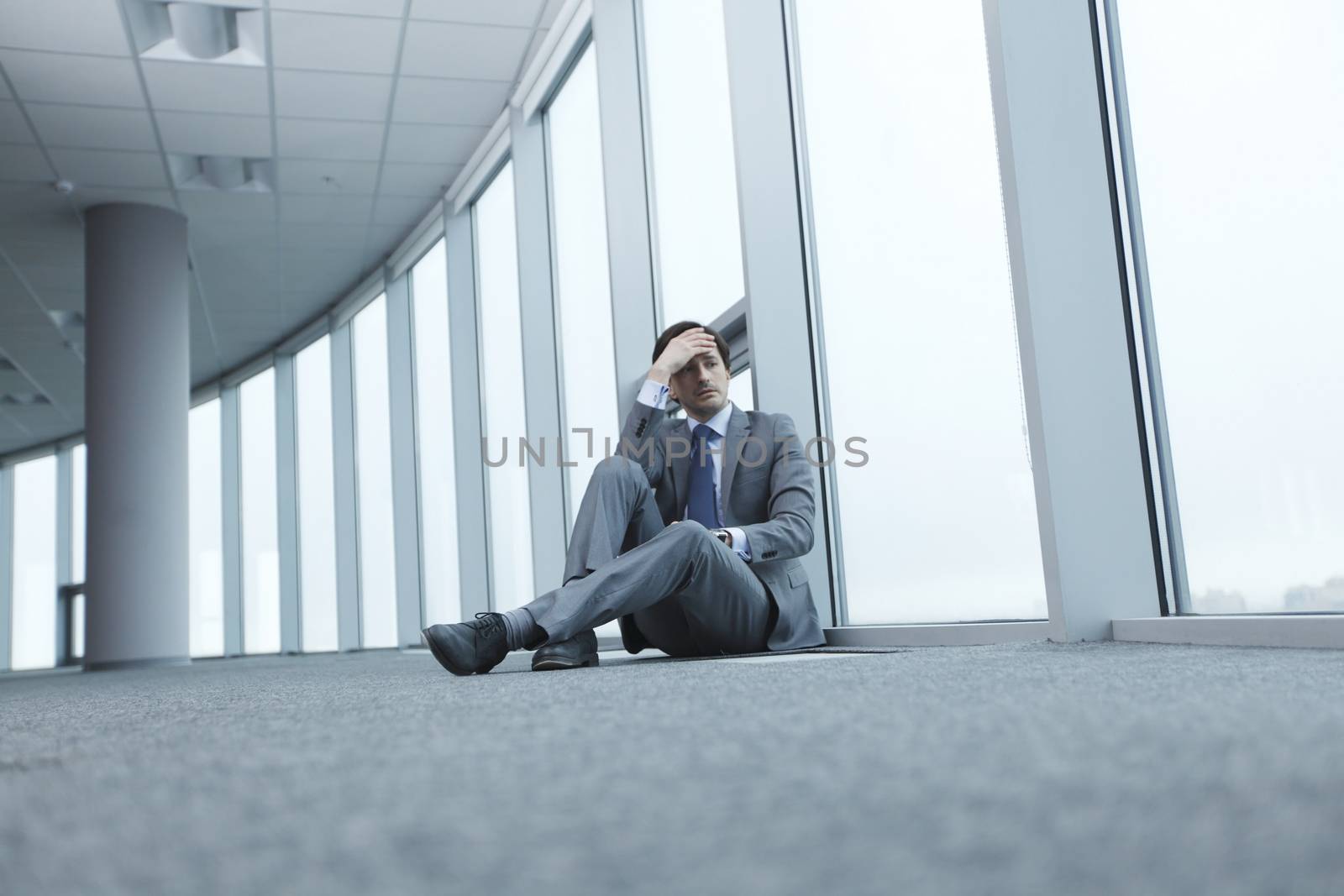 Businessman sitting on floor in office near window