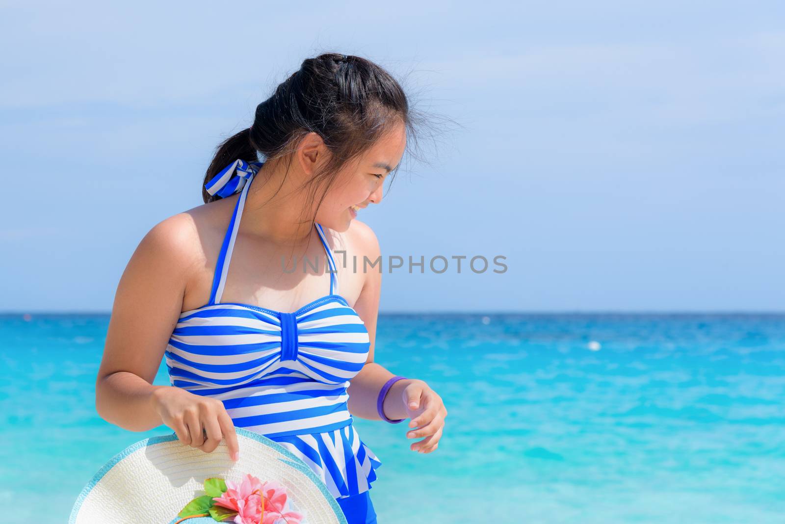 Tourist girl in a blue white striped swimsuit standing with happiness on the beautiful beach and sea during summer at Koh Miang Island, Mu Ko Similan National Park, Phang Nga province, Thailand