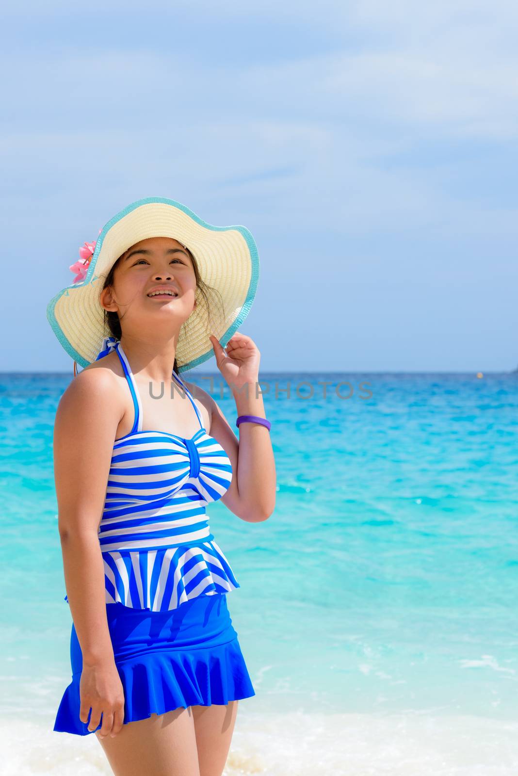 Tourist girl in a blue white swimsuit stand and looking up with happy on the beautiful beach and sea during summer at Koh Miang Island, Mu Ko Similan National Park, Phang Nga province, Thailand