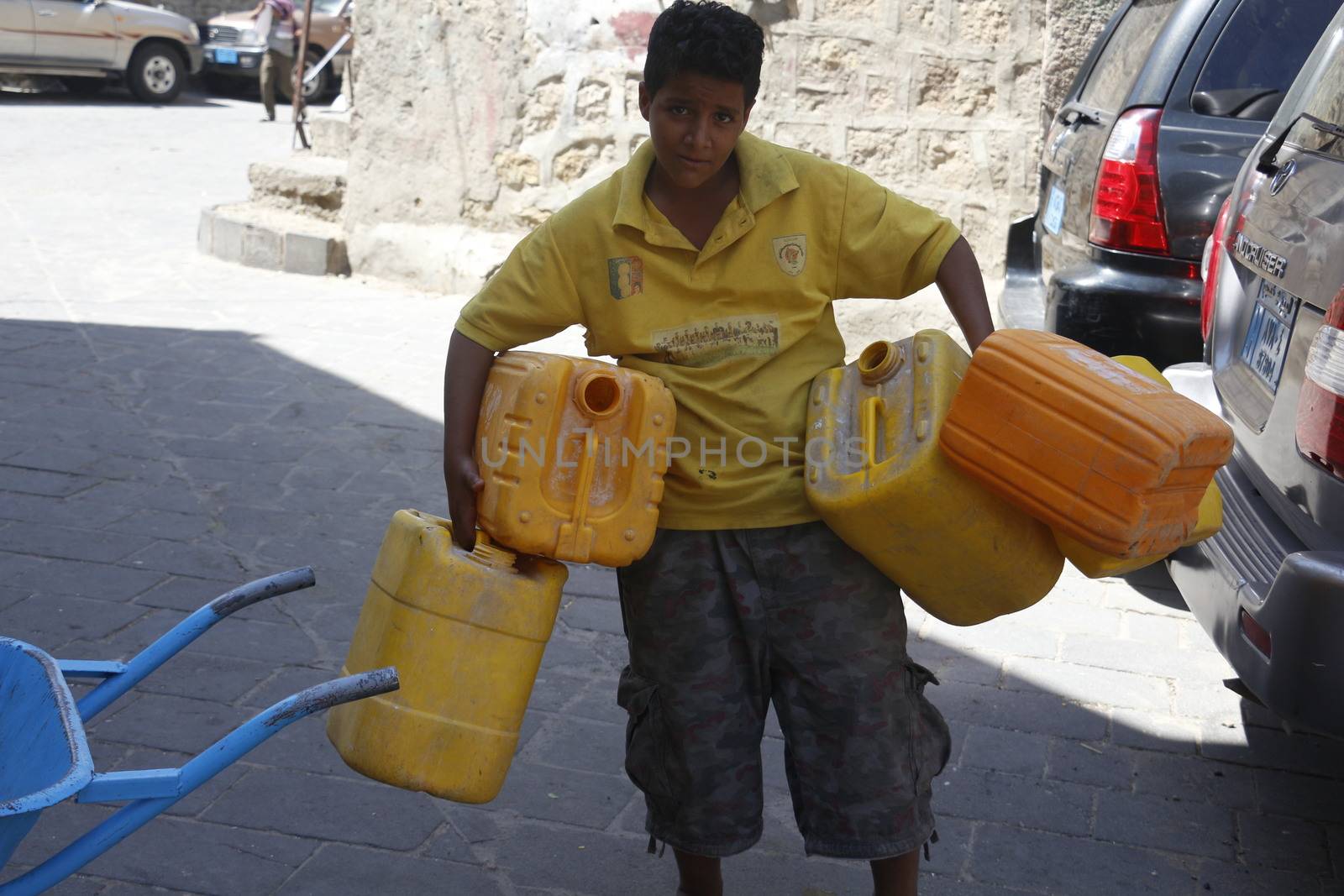 YEMEN, Taiz: A Yemeni boy carries jerrycans to fill them with water during a distribution of food and clean water in the Nasser school, outside Taiz (Ta'izz), western Yemen, on October 23, 2015. Many Yemenis are suffering from lack of basic services and resources, in a humanitarian disaster dramatically worsened by a blockade imposed by the Saudi-led coalition.
