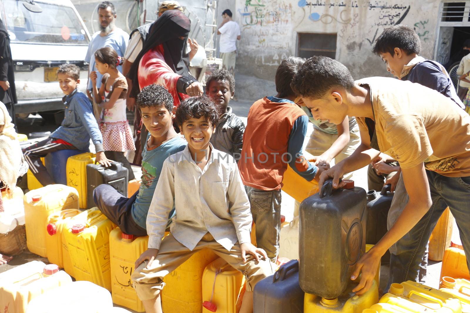 YEMEN, Taiz: Yemeni boys carry jerrycans to fill them with water during a distribution of food and clean water in the Nasser school, outside Taiz (Ta'izz), western Yemen, on October 23, 2015. Many Yemenis are suffering from lack of basic services and resources, in a humanitarian disaster dramatically worsened by a blockade imposed by the Saudi-led coalition.