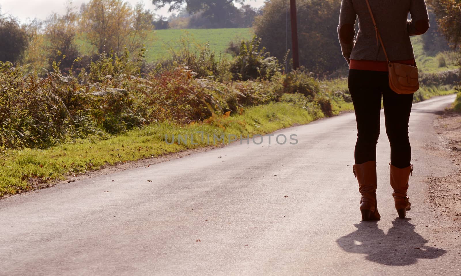 Young woman walks up a country lane alone by sarahdoow