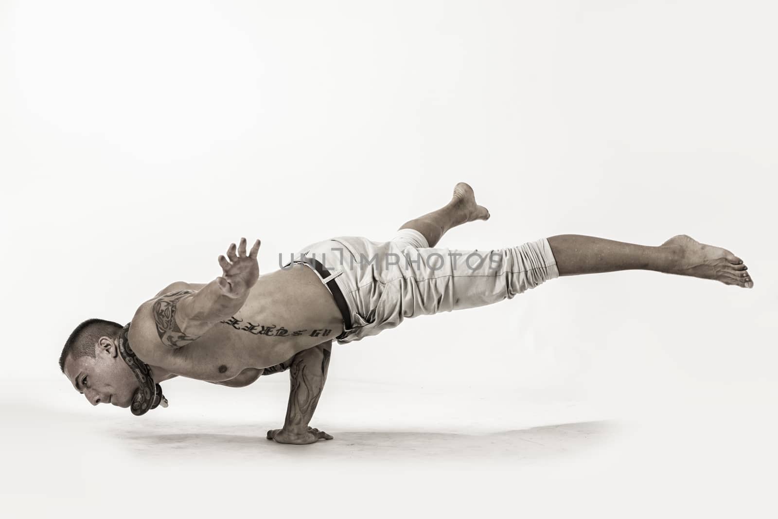 Muscular Shirtless Male Acrobatic Dancer Balancing on Arm and Hand in Studio Isolated on White Background