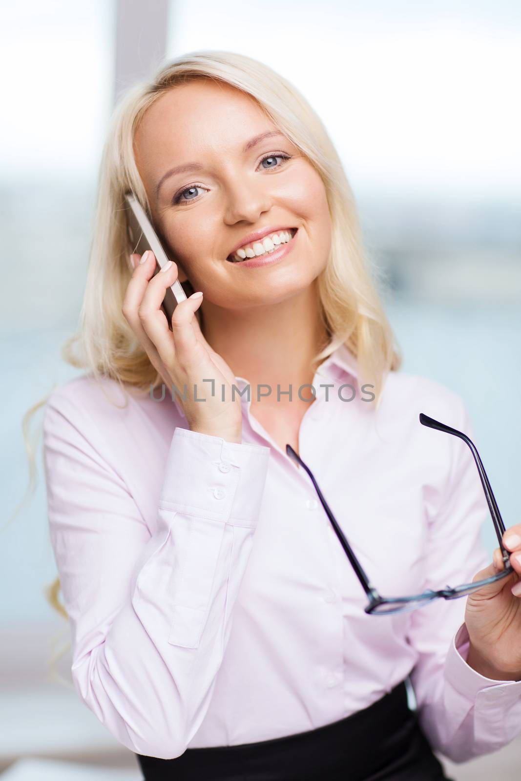 smiling businesswoman with smartphone in office by dolgachov