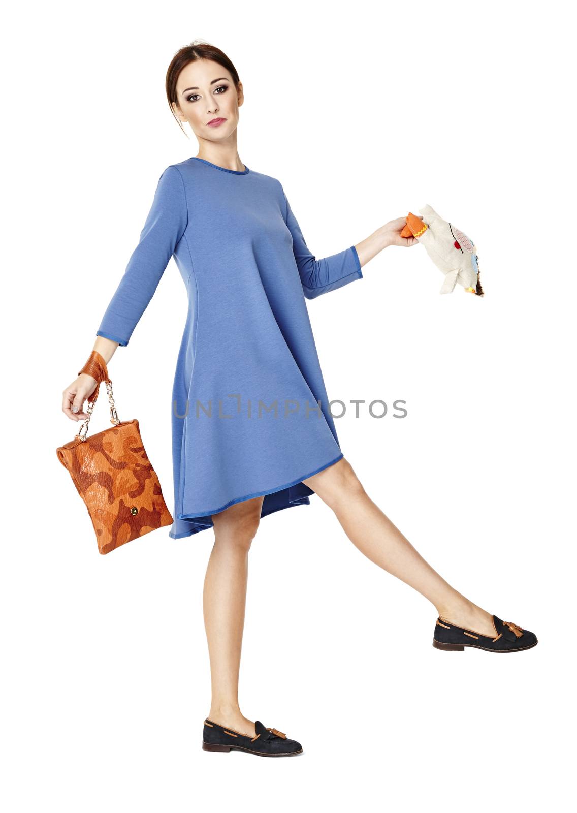 Woman in blue dress marching against a white background. She holds a bag and mascot.