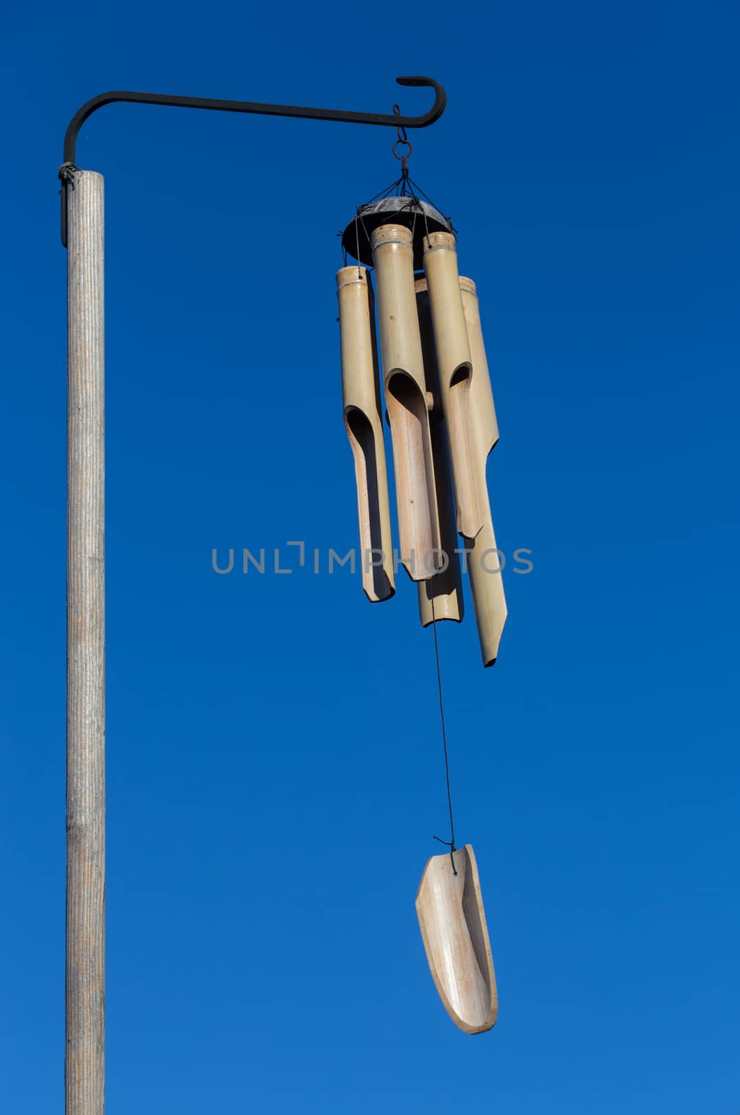 Bamboo wind chimes against a blue sky by johnborda