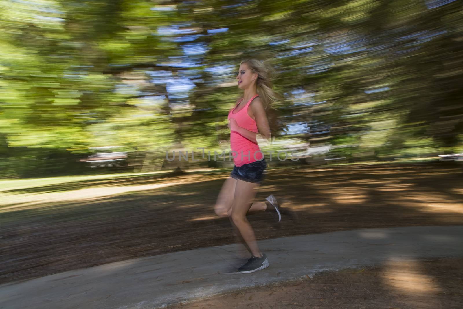 A young female jogger running through a wooded path