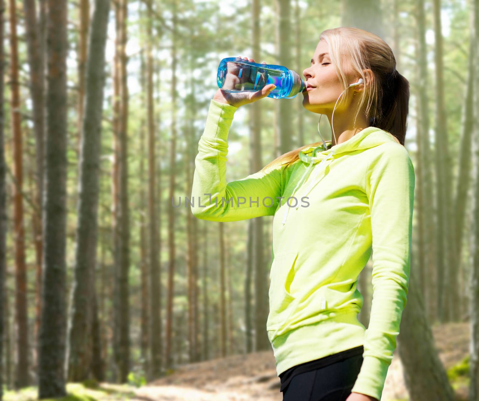 woman drinking water after doing sports outdoors by dolgachov