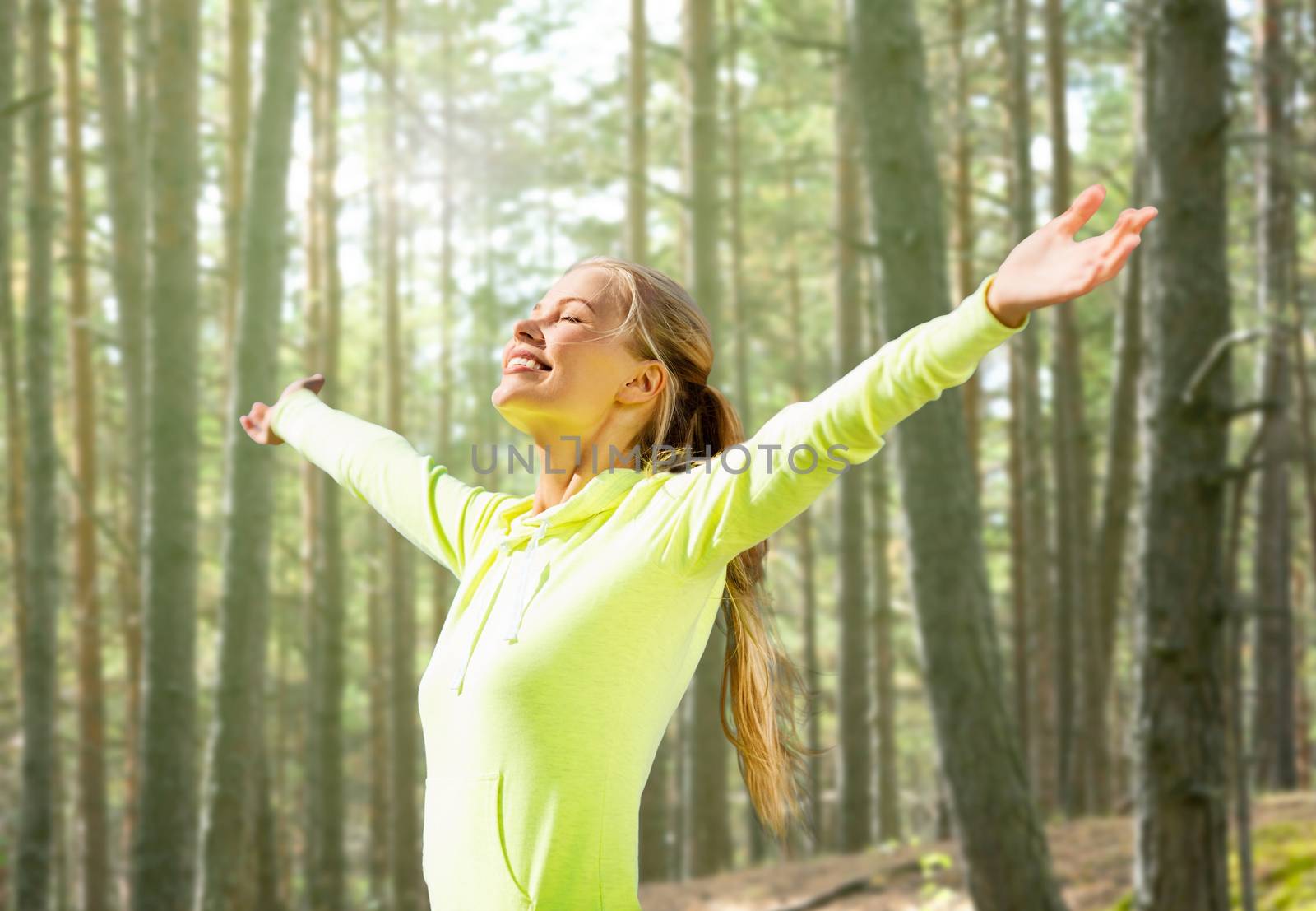 fitness, sport, happiness and people concept - happy woman raising hands over woods background