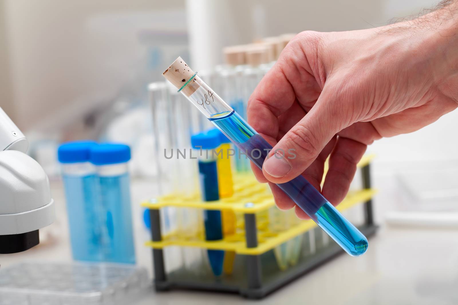 A test tube with blue liquid in the hand. Science lab research