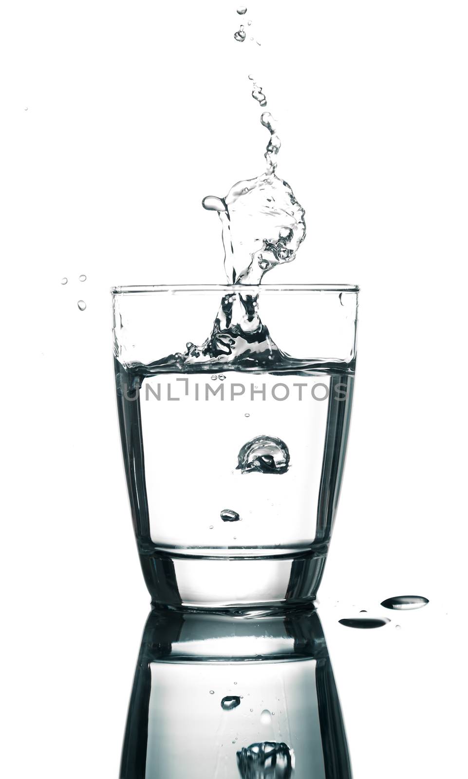 pouring water on a glass on white background by motorolka