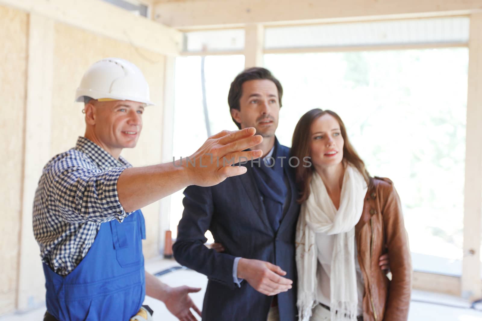 Worker in workwear shows new house to a couple