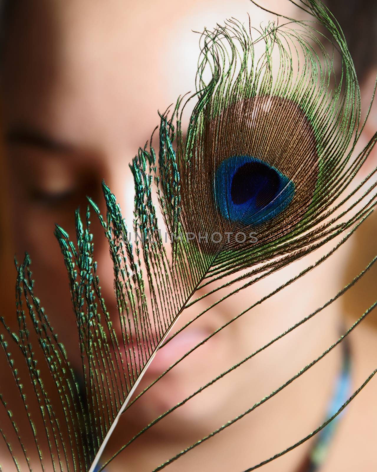 A peacock feather infront of a womans face.