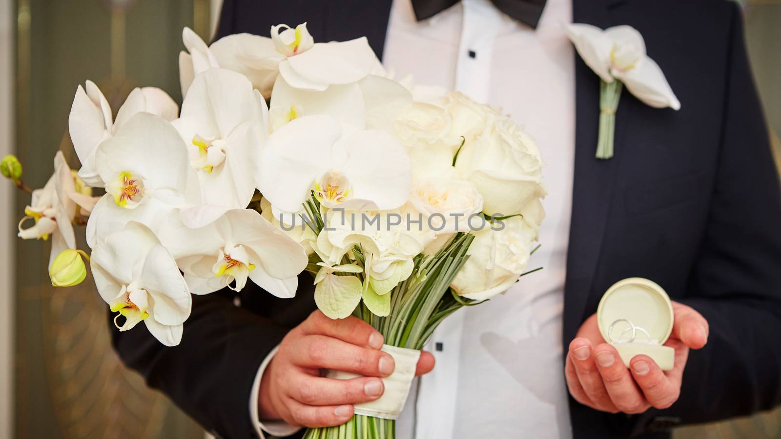 The groom with wedding rings and bouquet