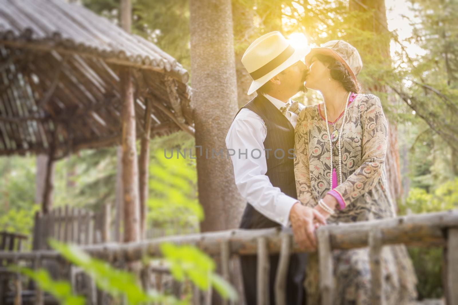 1920s Dressed Romantic Couple Kissing on Wooden Bridge by Feverpitched