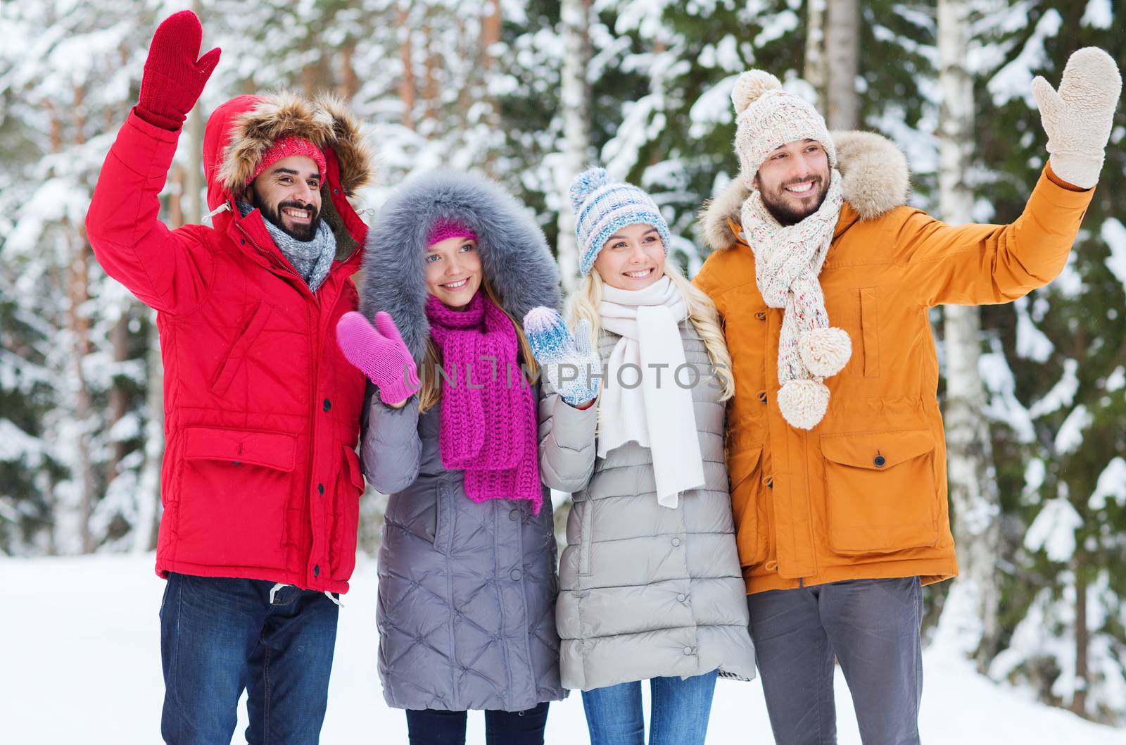 love, relationship, season, friendship and people concept - group of smiling men and women waving hands in winter forest