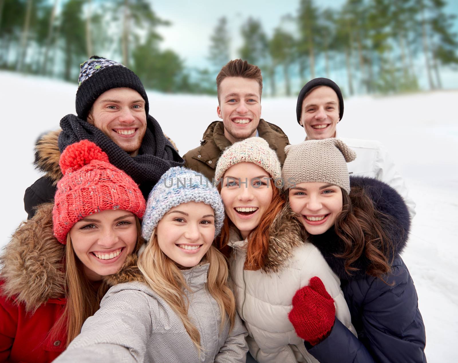 winter, technology, friendship and people concept - group of smiling men and women taking selfie outdoors