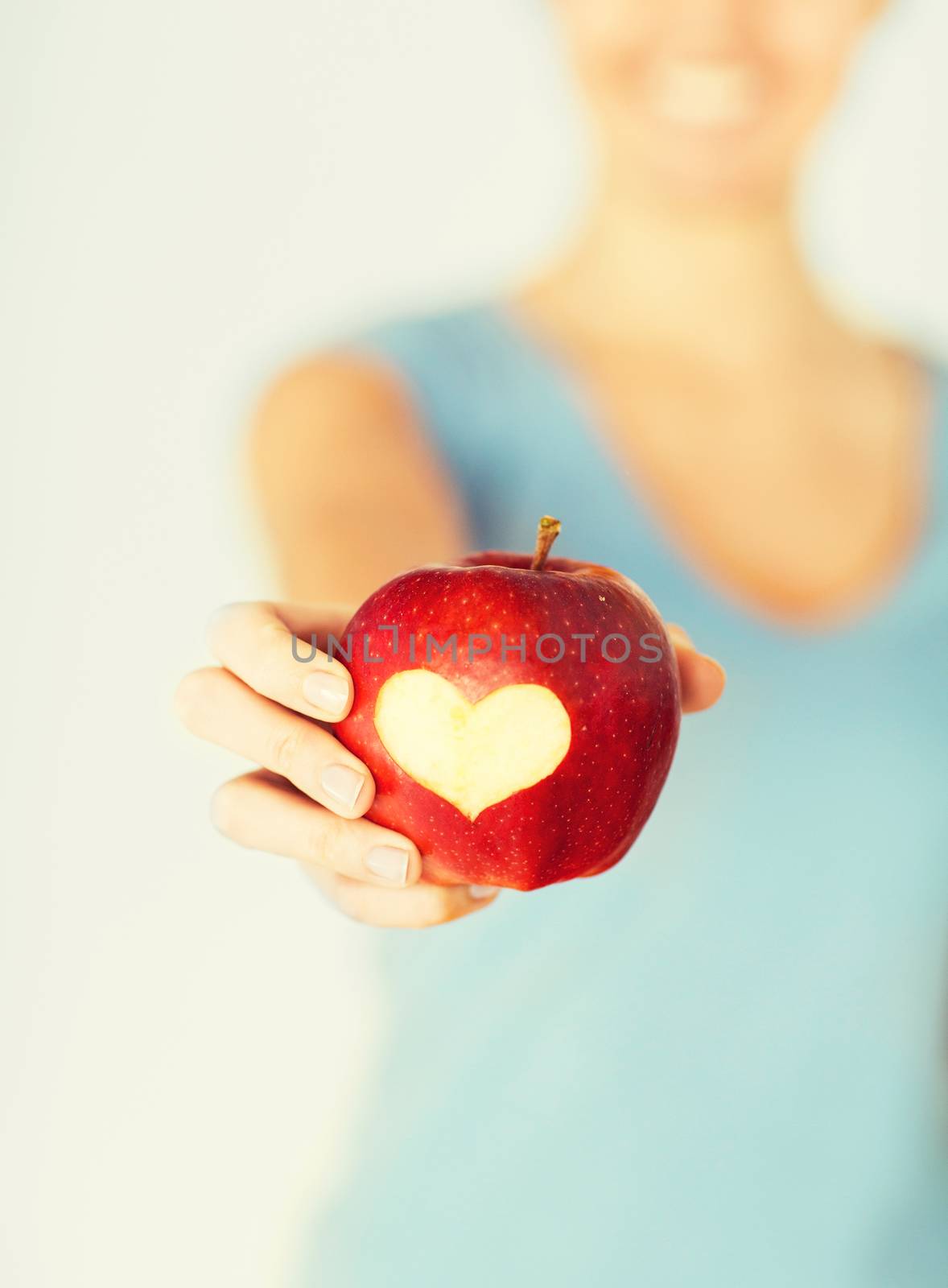 healthy food and lifestyle - woman hand holding red apple with heart shape