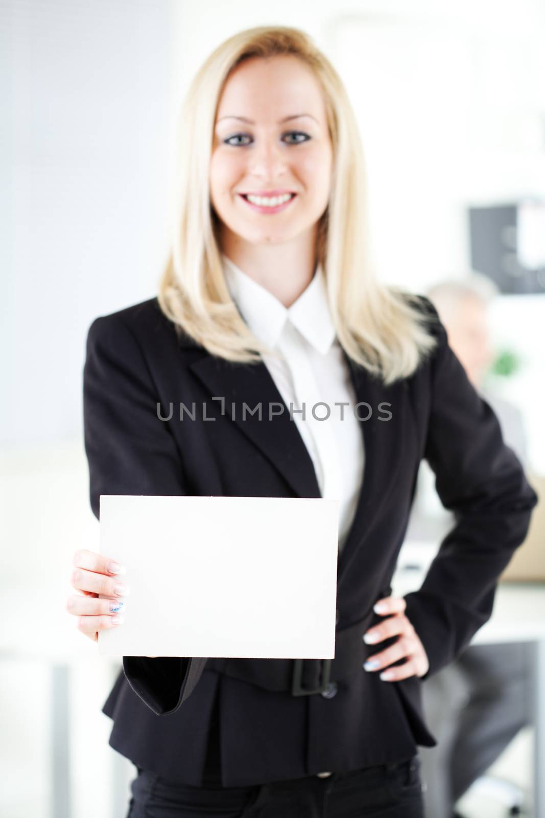 Beautiful young businesswoman holding Blank business card in the office. Looking at camera. Selective Focus. Focus on paper.