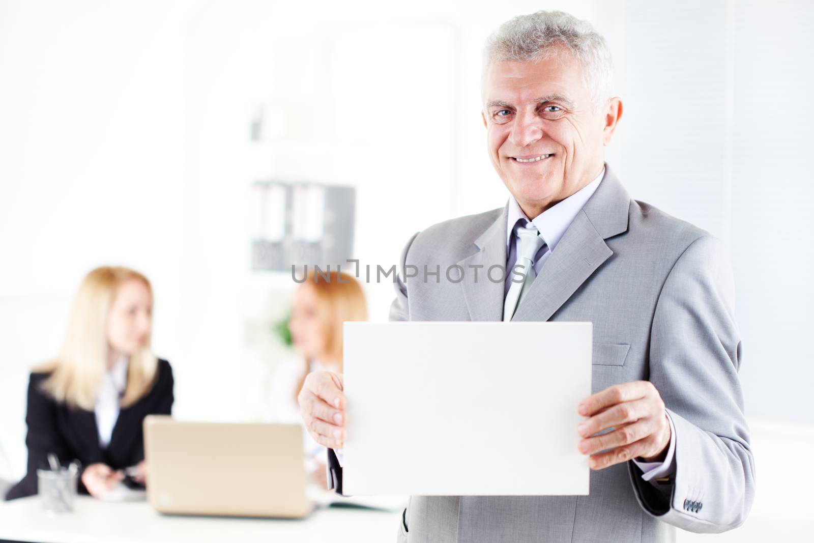 Happy senior businessman holding Blank business card in the office. Looking at camera. Selective Focus.