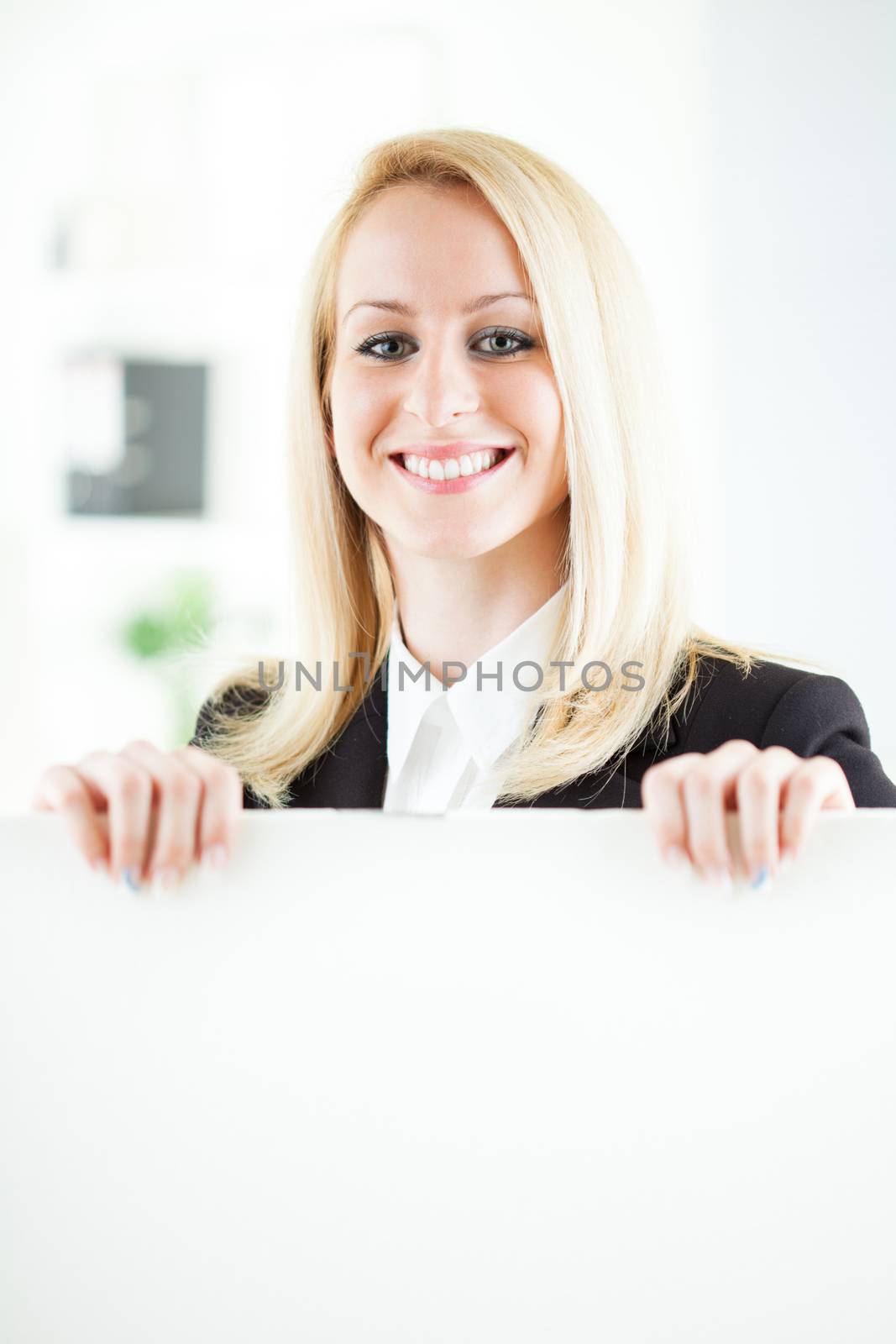 Beautiful young businesswoman holding Blank business board in the office. Looking at camera. Selective Focus.