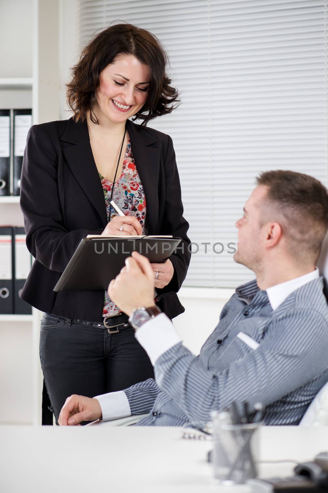 Happy Business people Working together in the office. Manager with his secretary. He is dictating something to her.