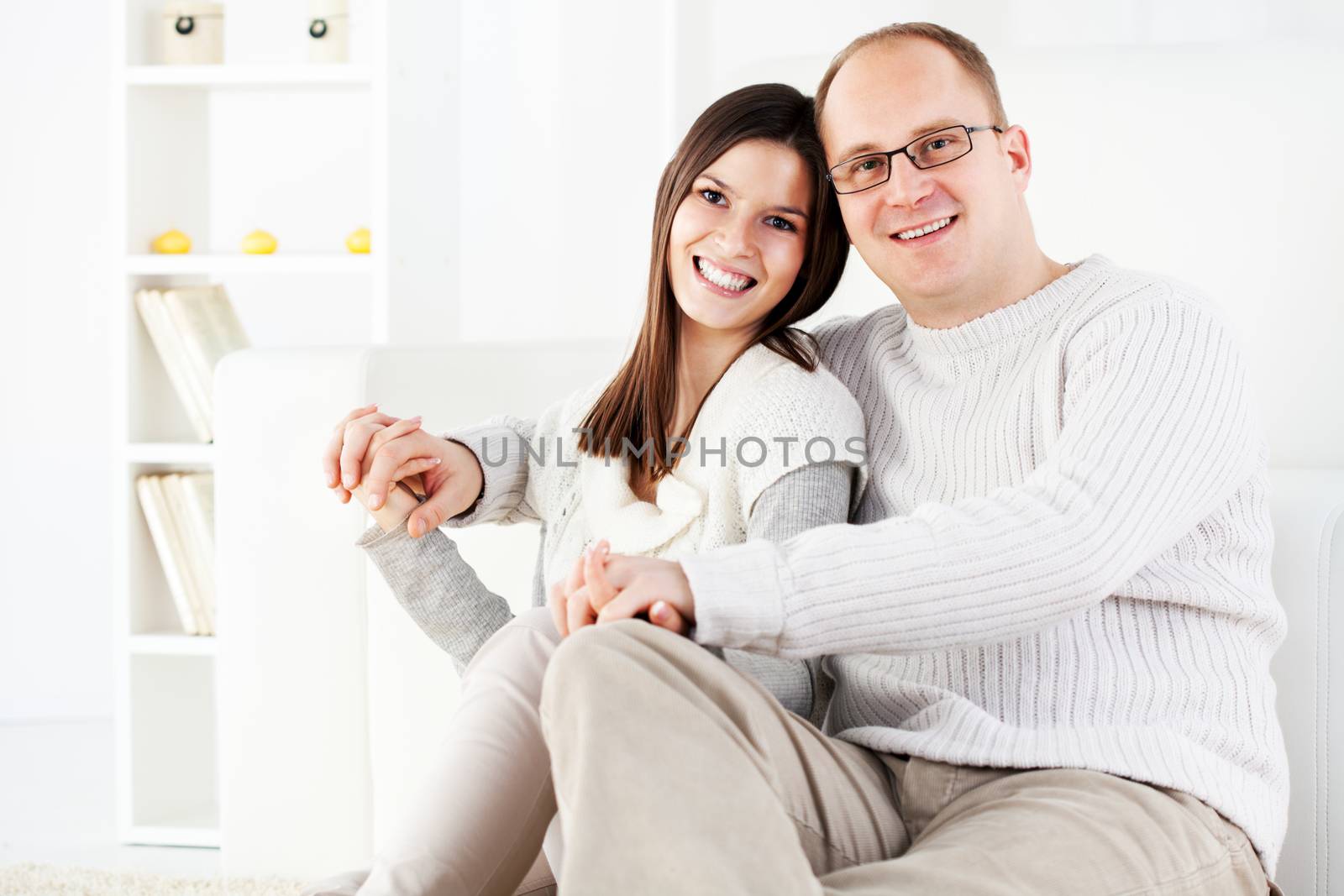 Happy beautiful Young couple is holding hands in home interior. Looking at camera.