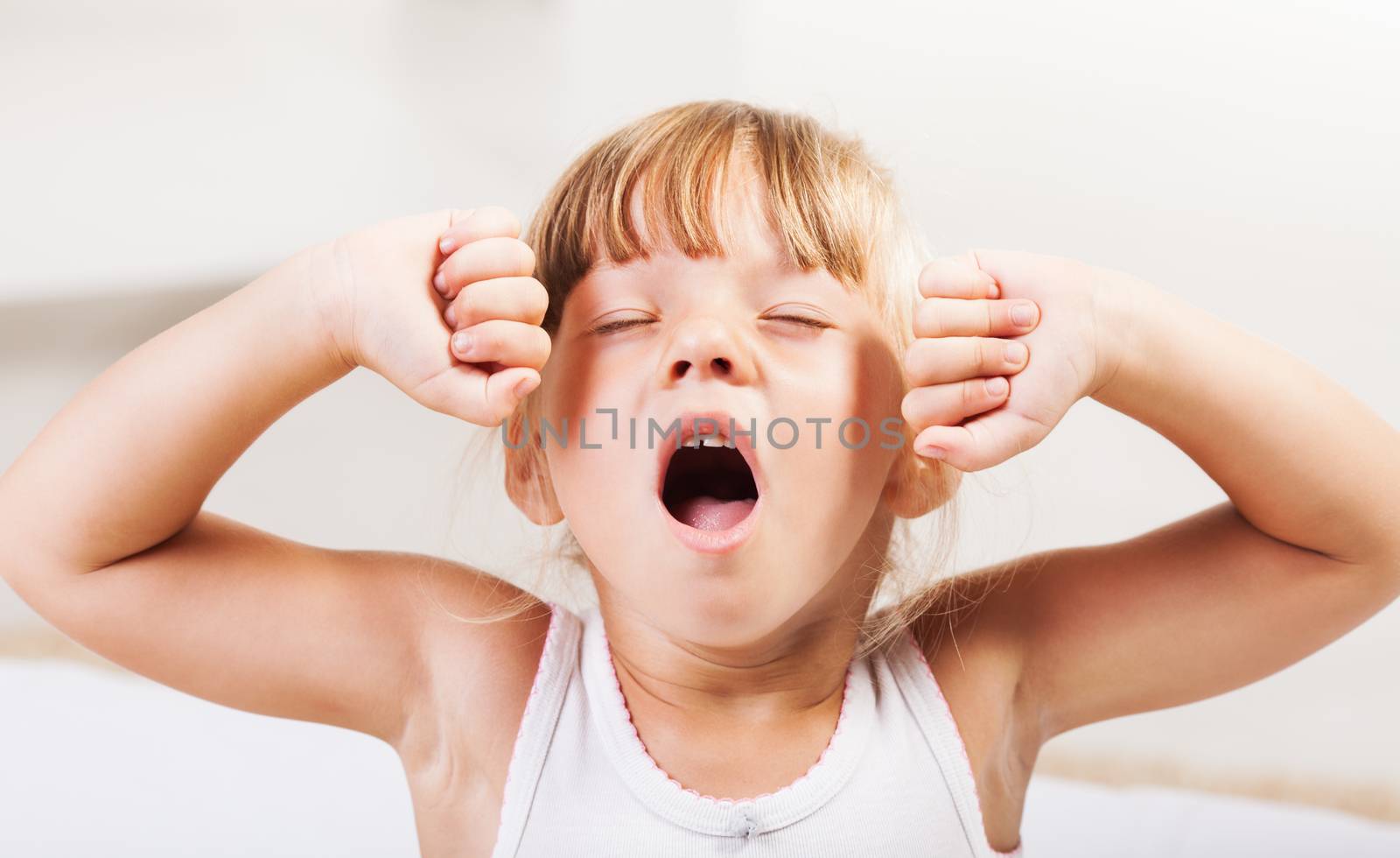 Cute little girl stretching in bed.