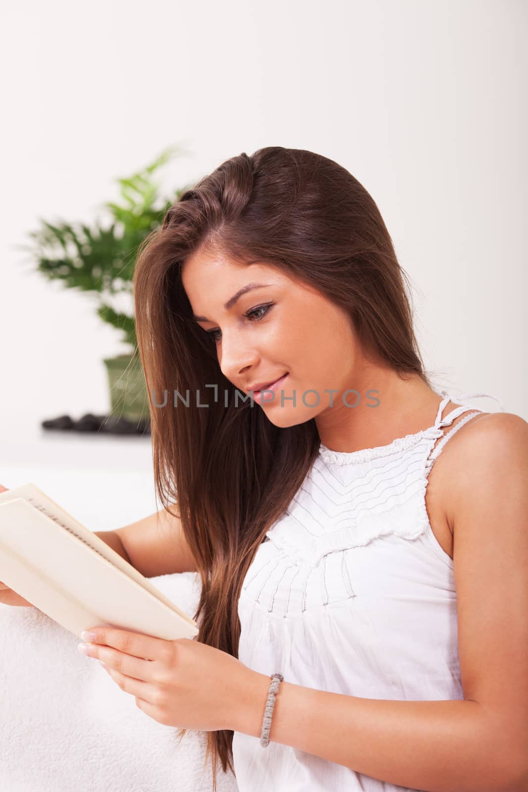 Beautiful young girl sitting and reading a book.