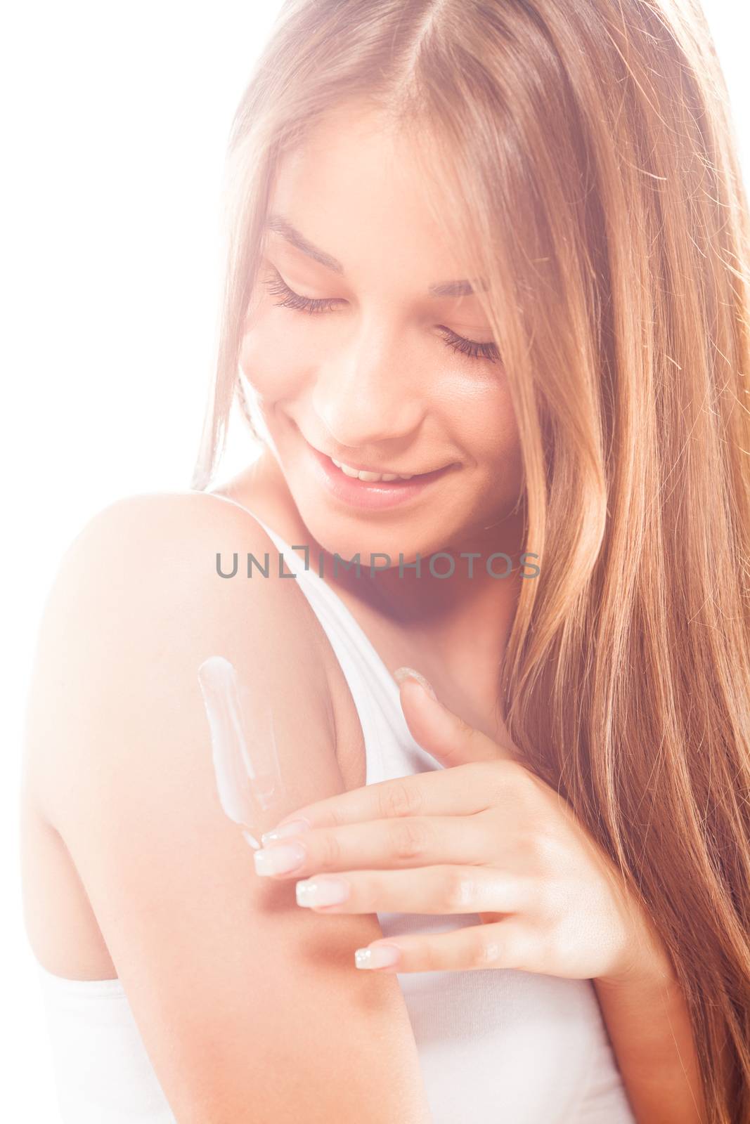 Beautiful young woman applying body lotion.