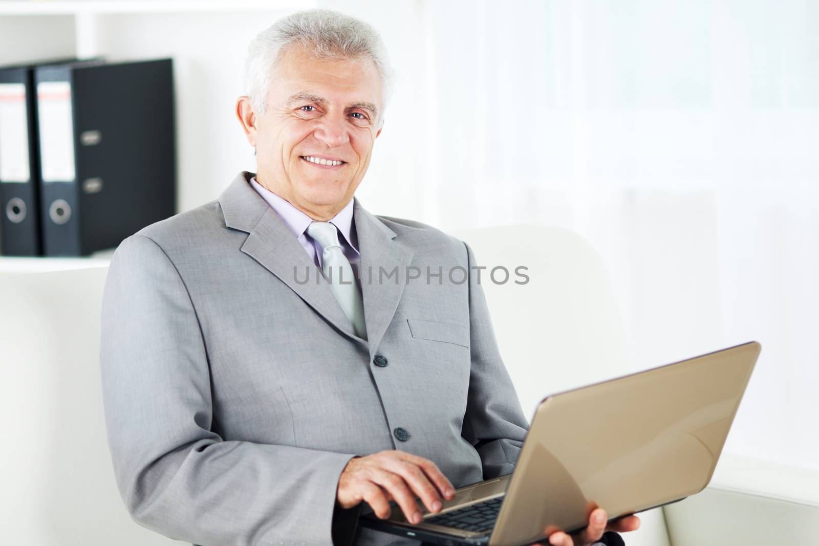 Happy Senior businessman working at home on laptop.