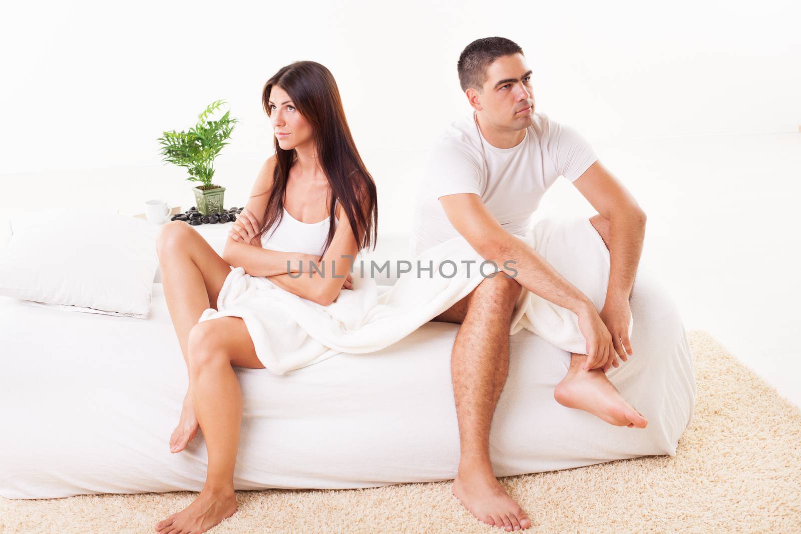 Angry Young couple sitting on the bed because of  Relationship Difficulties.