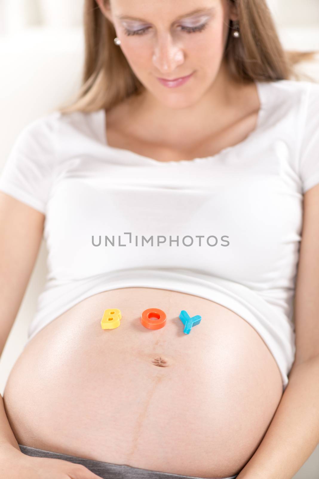 Multi Colored letters spelling Boy on a pregnant belly.