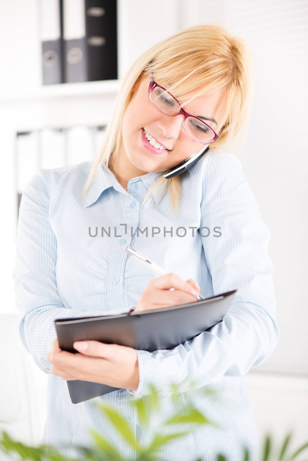 Busy Beautiful Businesswoman with glasses use mobile phone in the office.