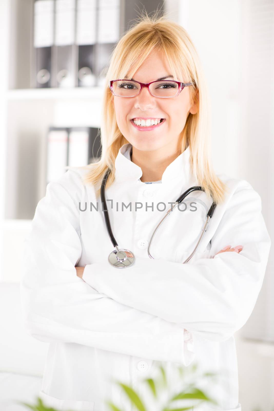 Portrait of a young woman doctor with stethoscope standing in her office.