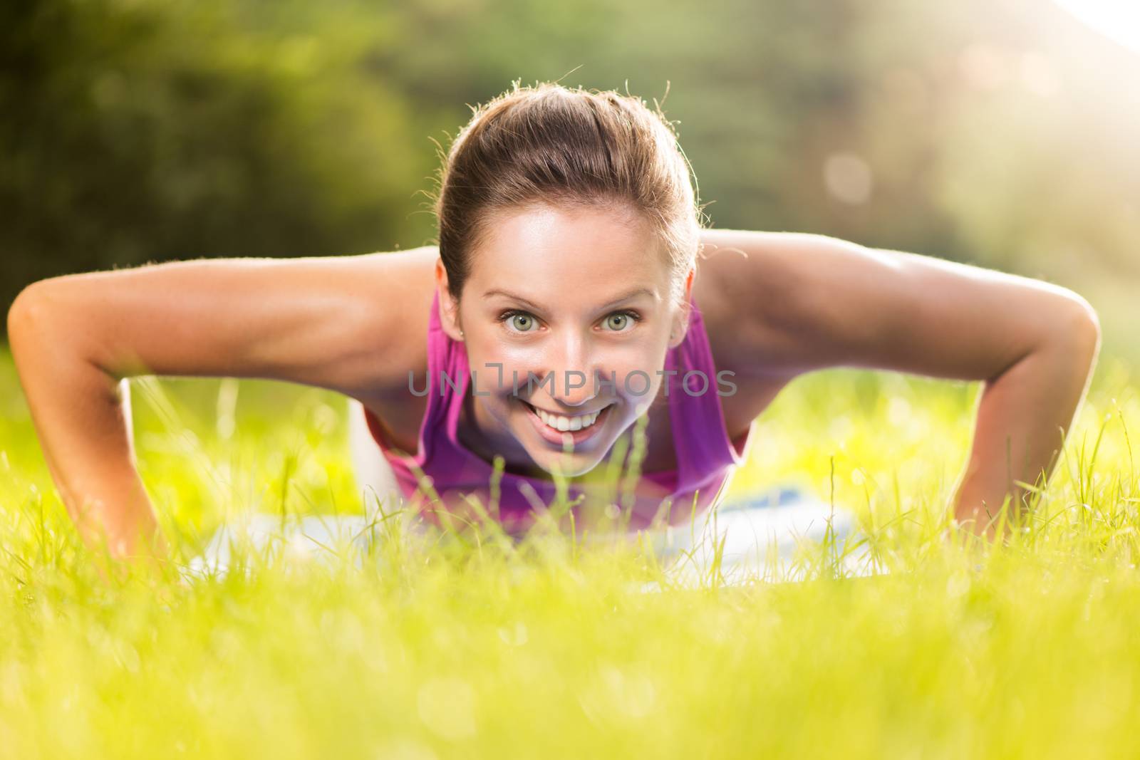 Cute young woman doing push-ups in the park.