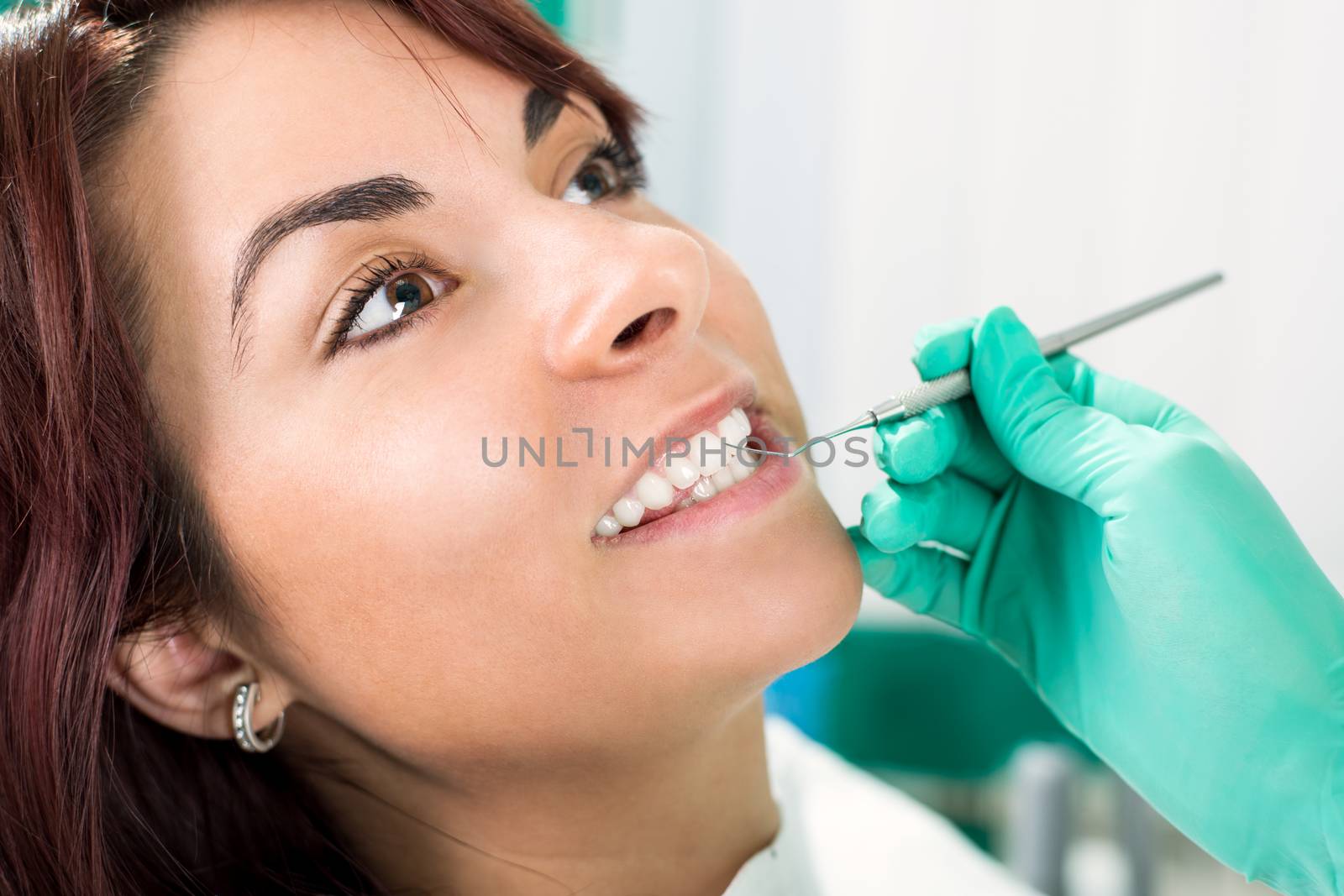 Dentist examination and cleaning patient teeth in the office with metal dental pick tool.