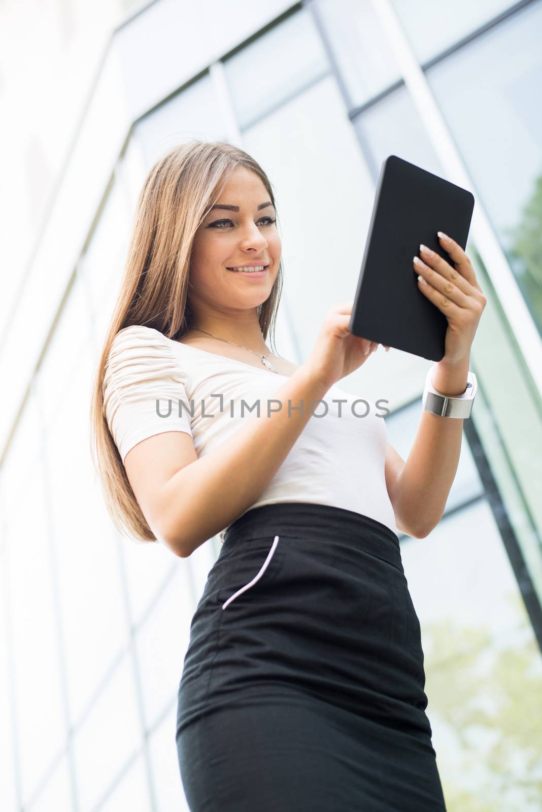 Happy Businesswoman standing on the street in front of Office Building and using a Tablet PC.