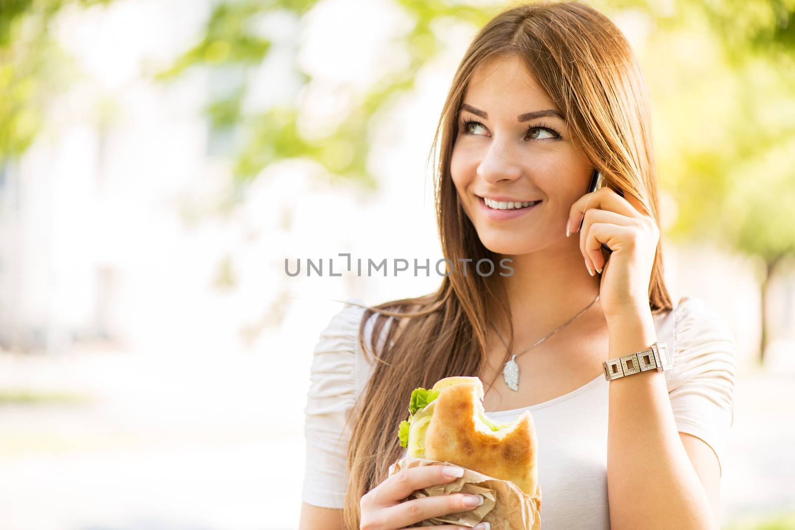 Portrait of beautiful, smiling young woman taking a break for breakfast and using a Cell Phone.