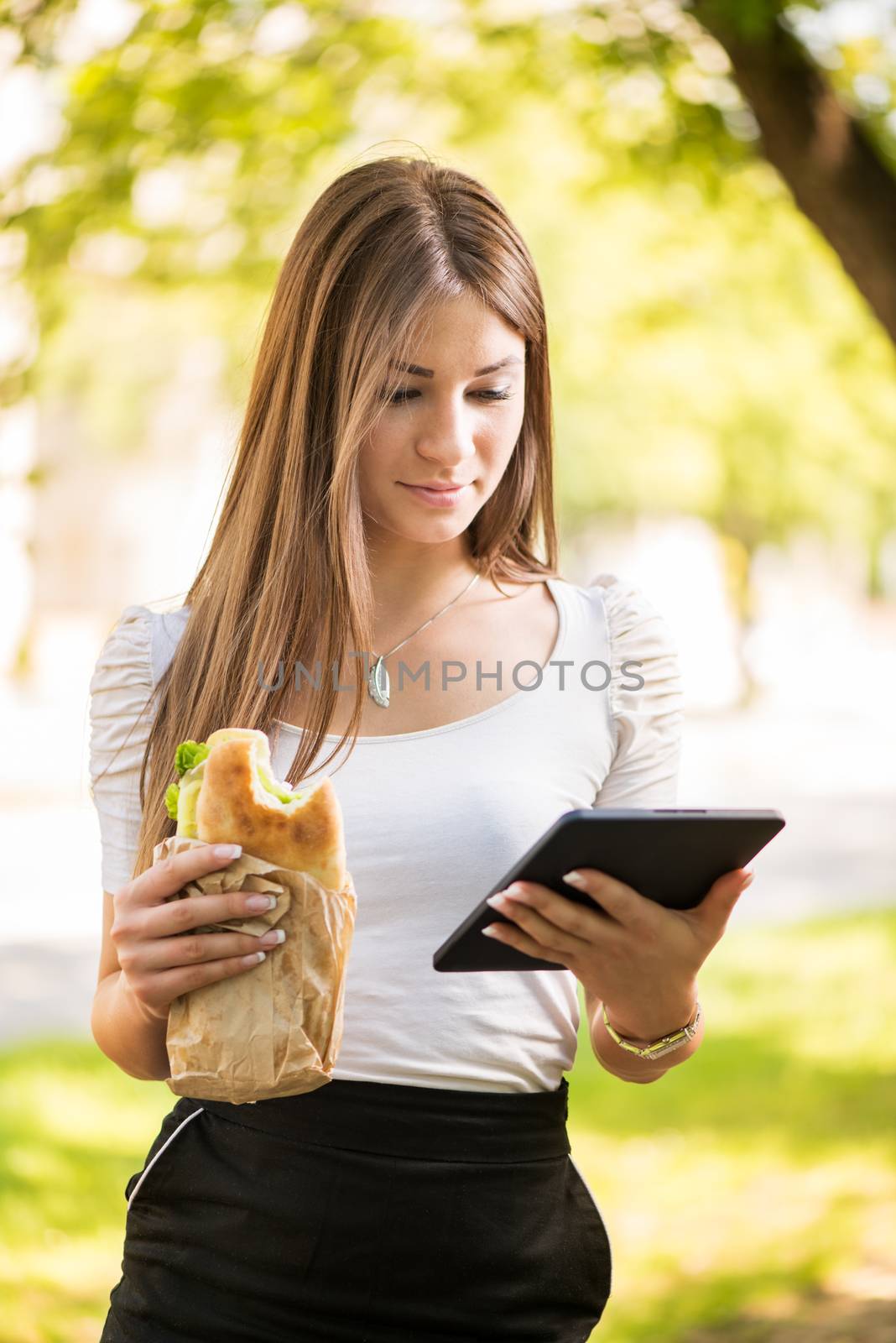 Beautiful young woman taking a break for breakfast and using a Tablet PC.