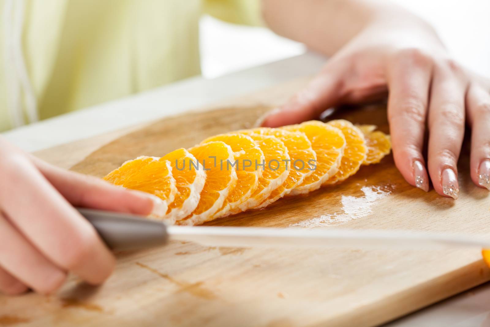 Female hands Cutting Orange in a kitchen. Close-up. Selective Focus.